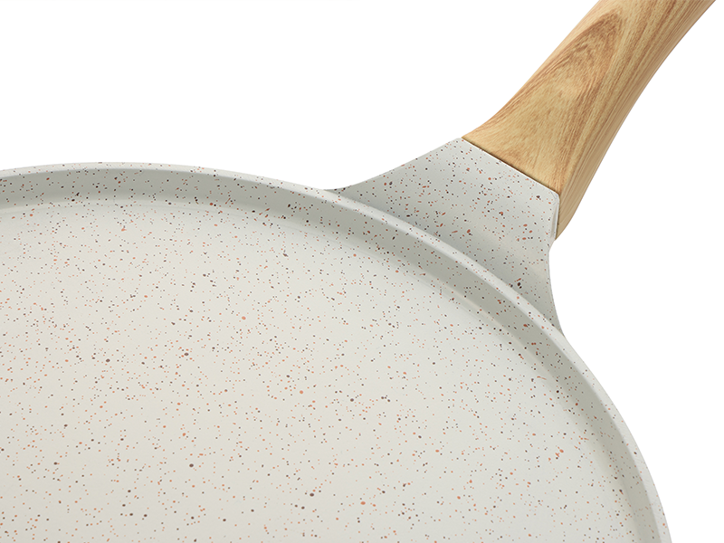 Poêle antiadhésive avec revêtement en céramique blanche mouchetée et manche en bois clair, vu du haut