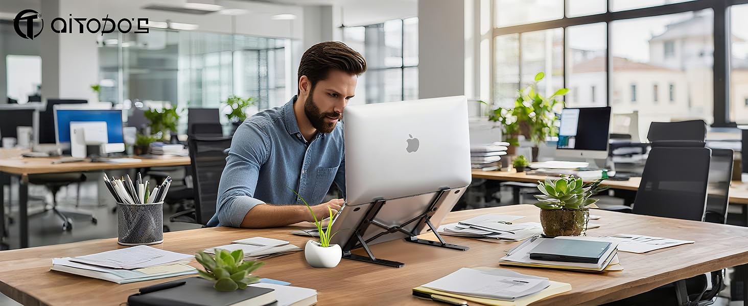Espace de travail moderne avec bureau en bois, plantes et configuration informatique dans un environnement lumineux et éclairé naturellement.